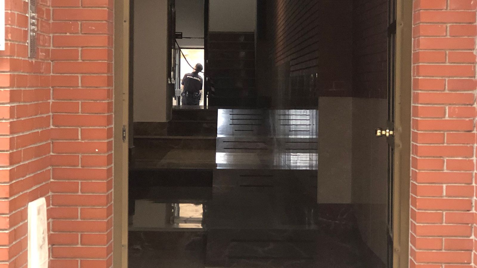 Un agente de la Policía Nacional, al fondo, inspecciona el patio interior del edificio durante la mañana de este jueves.