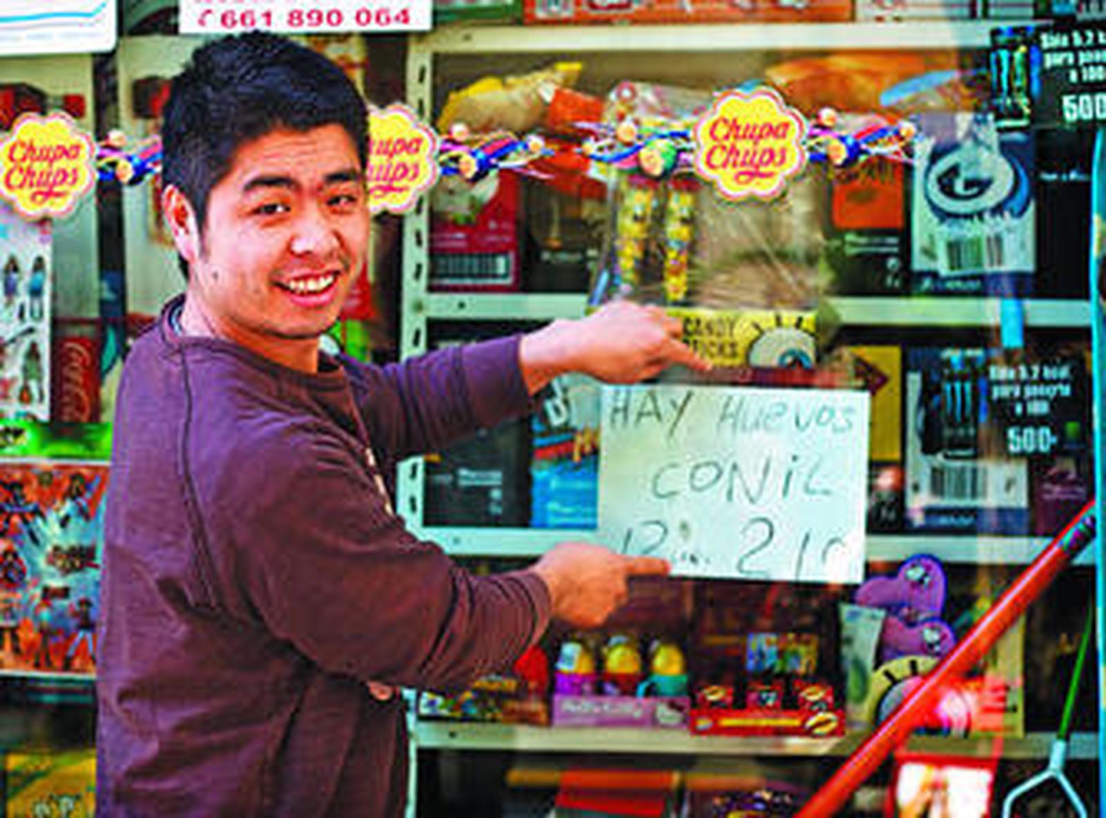 Lin, en la puerta de su establcimiento de Cádiz, mostrando el cartel en el que ofrece huevos de Conil.