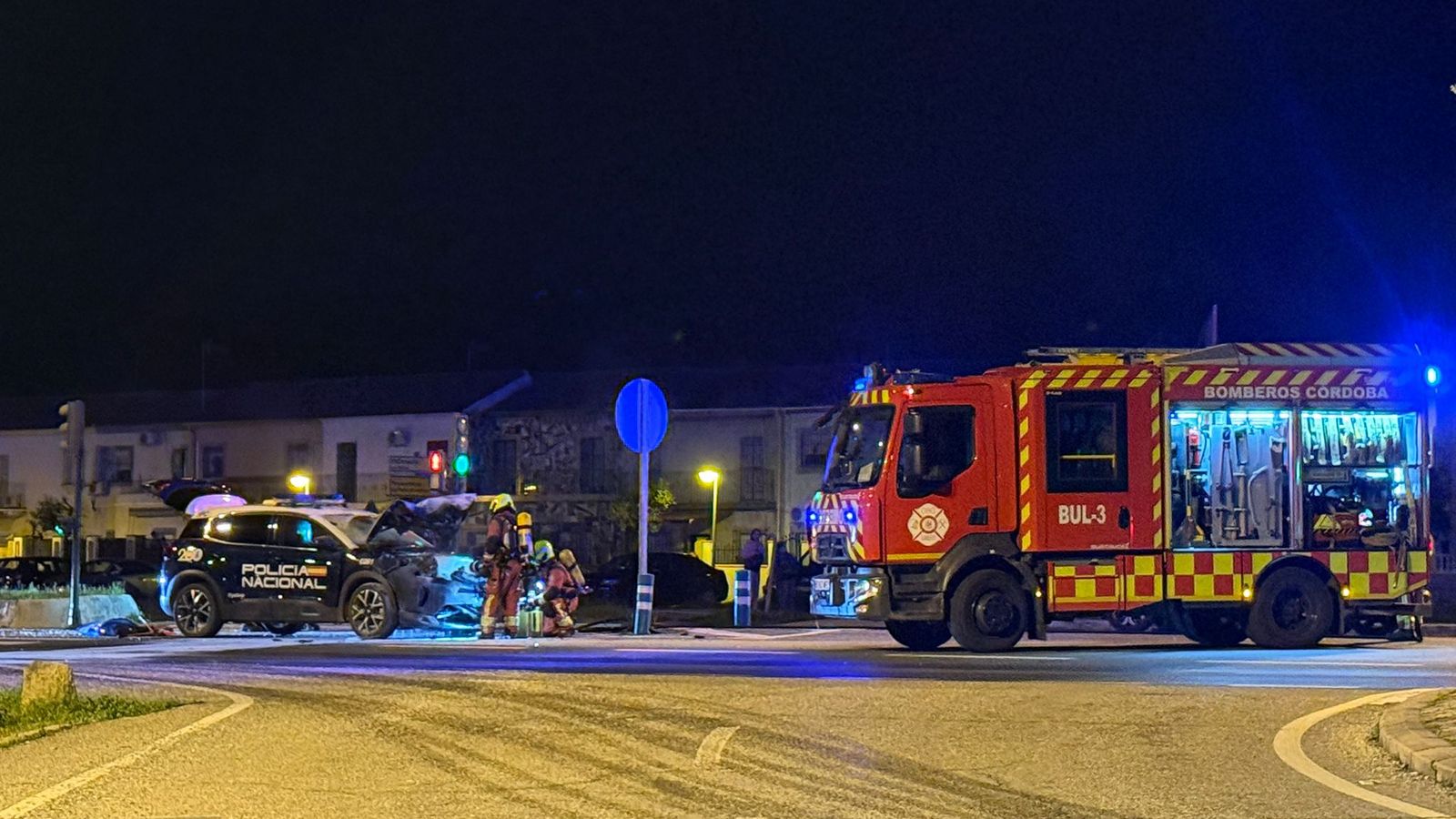 El coche policial siniestrado y los bomberos que acudieron al lugar.