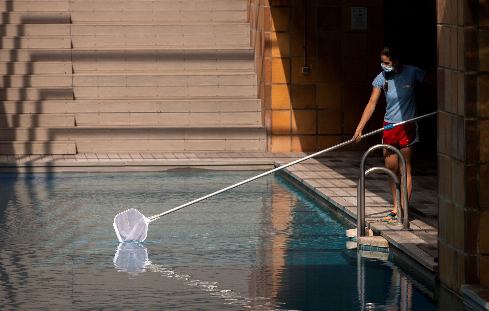 Una socorrista limpia una piscina comunitaria.