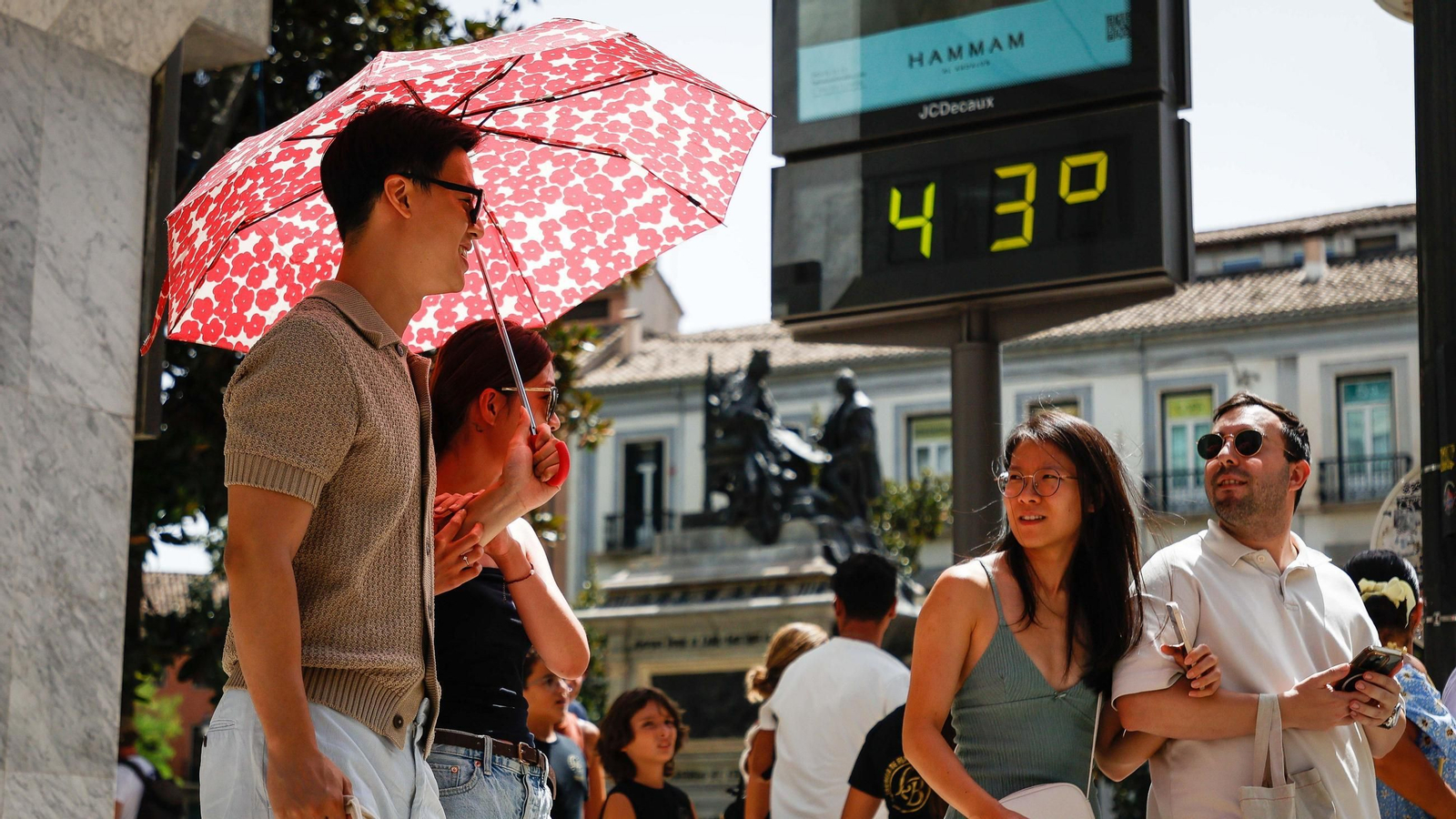 Turistas se protegen de los rayos del sol frente a un termómetro el lunes, 4 de agosto, en Granada