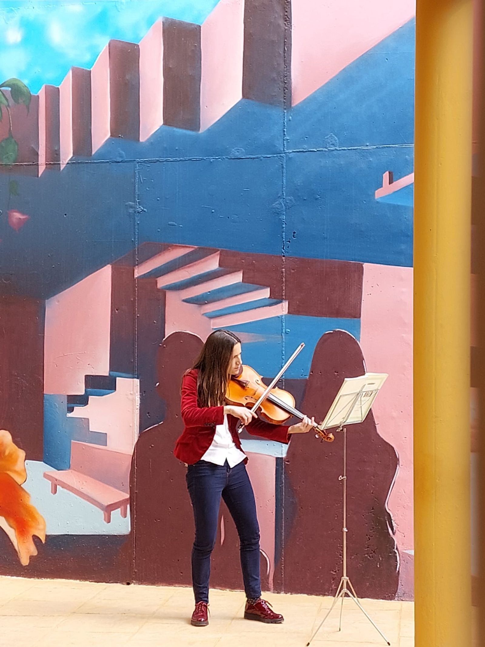Una joven toca el violín durante la inauguración del mural