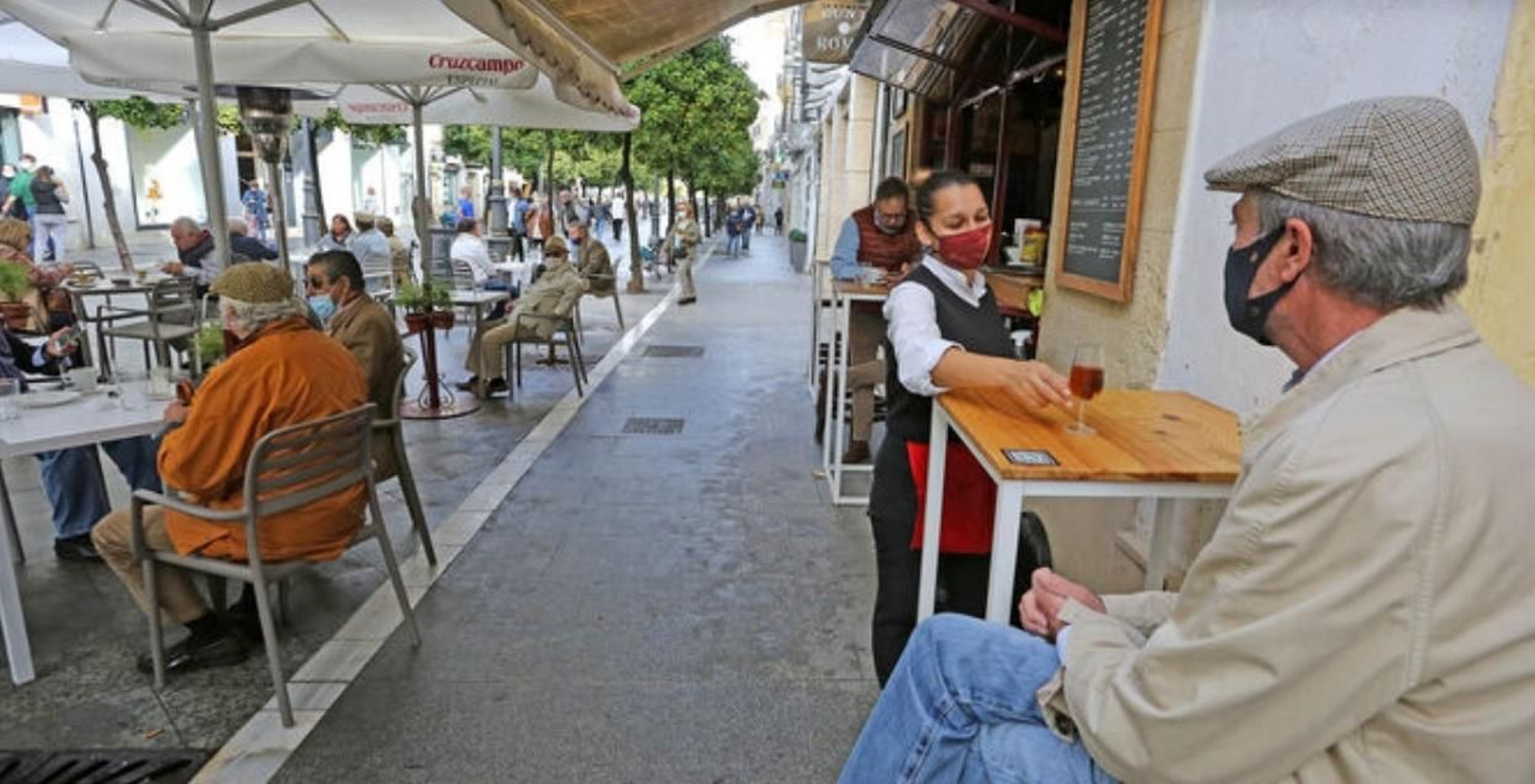 Una camarera sirve una copa de jerez a un cliente de un bar del centro de Jerez.