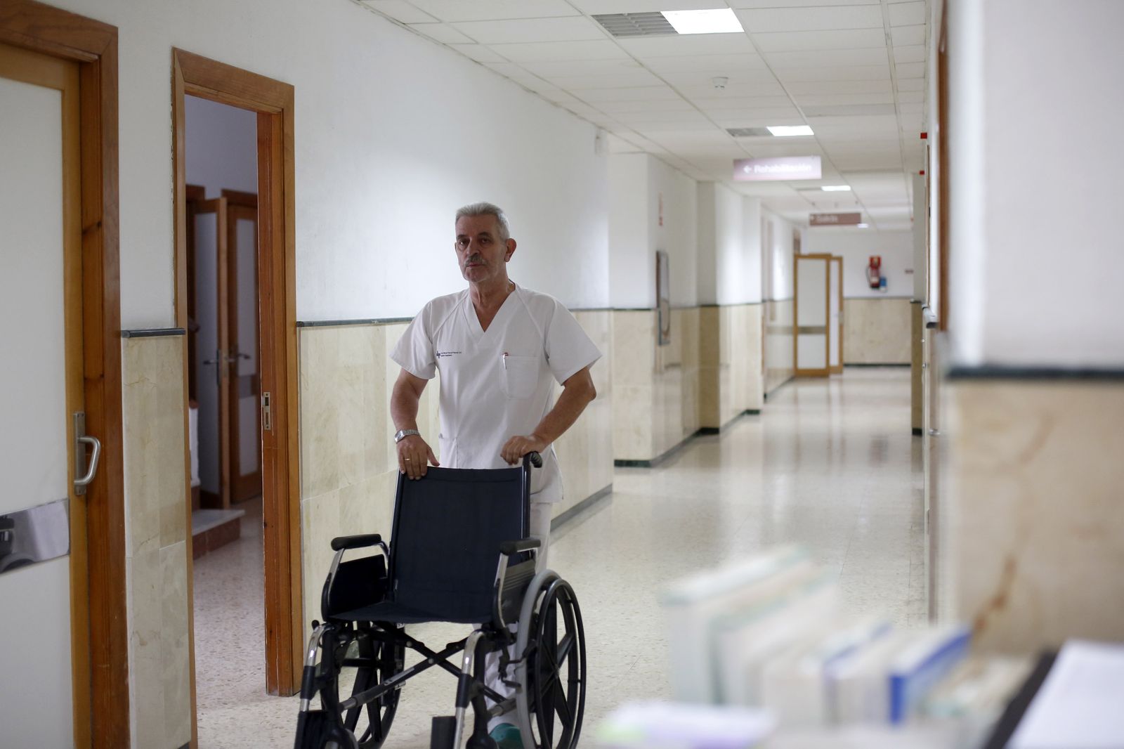 Un empleado del Hospital San Rafael empuja una silla de ruedas.