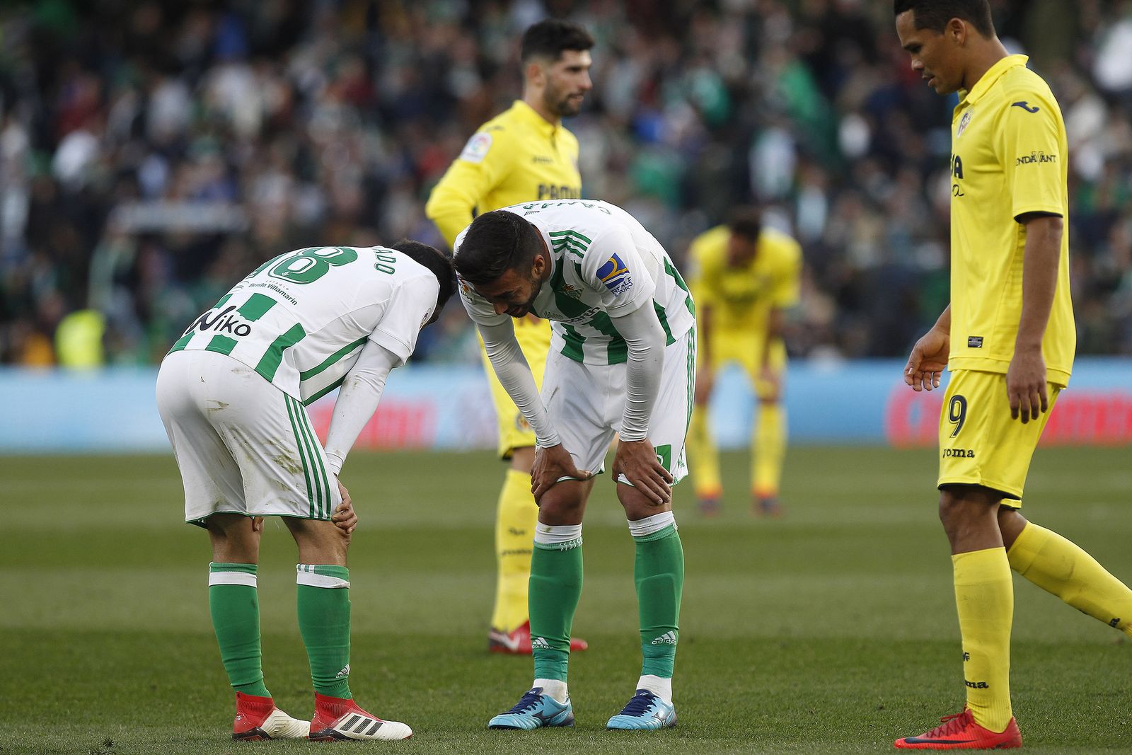 Los jugadores del Betis Guardado y Camarasa conversan antes del lanzamiento de un tiro libre contra la portería de Asenjo.
