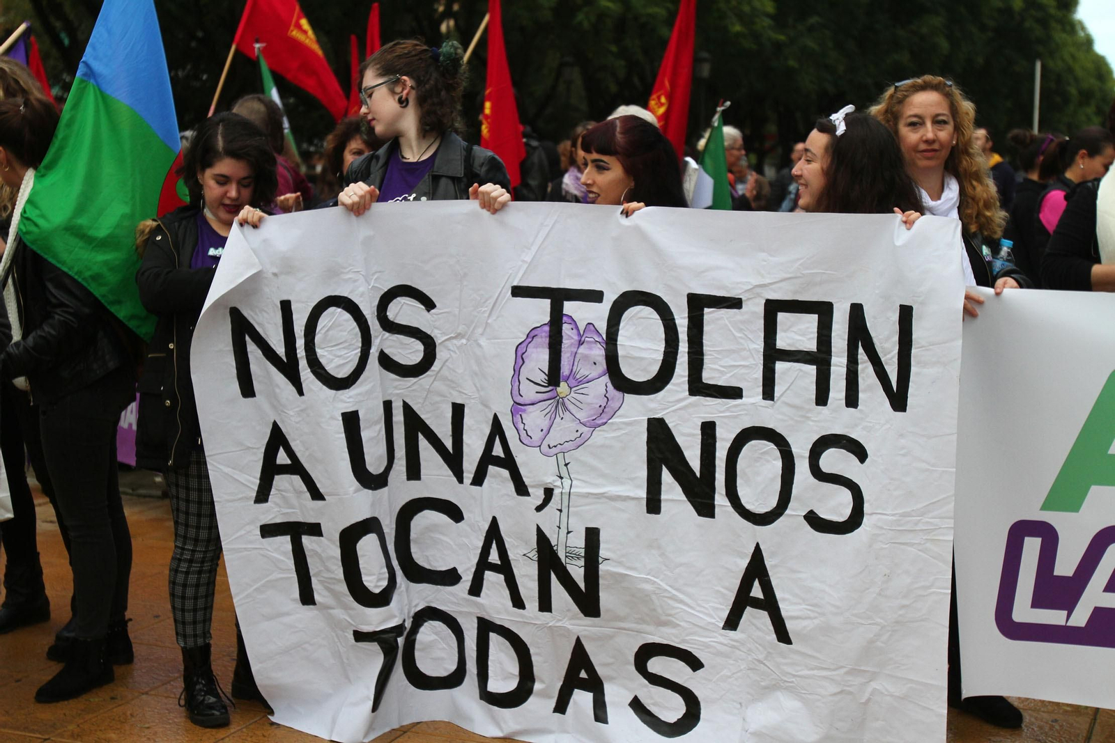 Jóvenes onubenses tras una pancarta de la manifestación del 25-N de 2018.