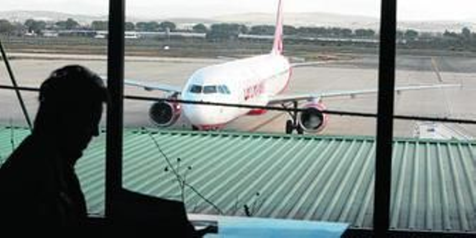 Un pasajero en la cafetería del aeropuerto de Jerez, desde donde se observa un avión de Air Berlin, en una imagen de archivo.