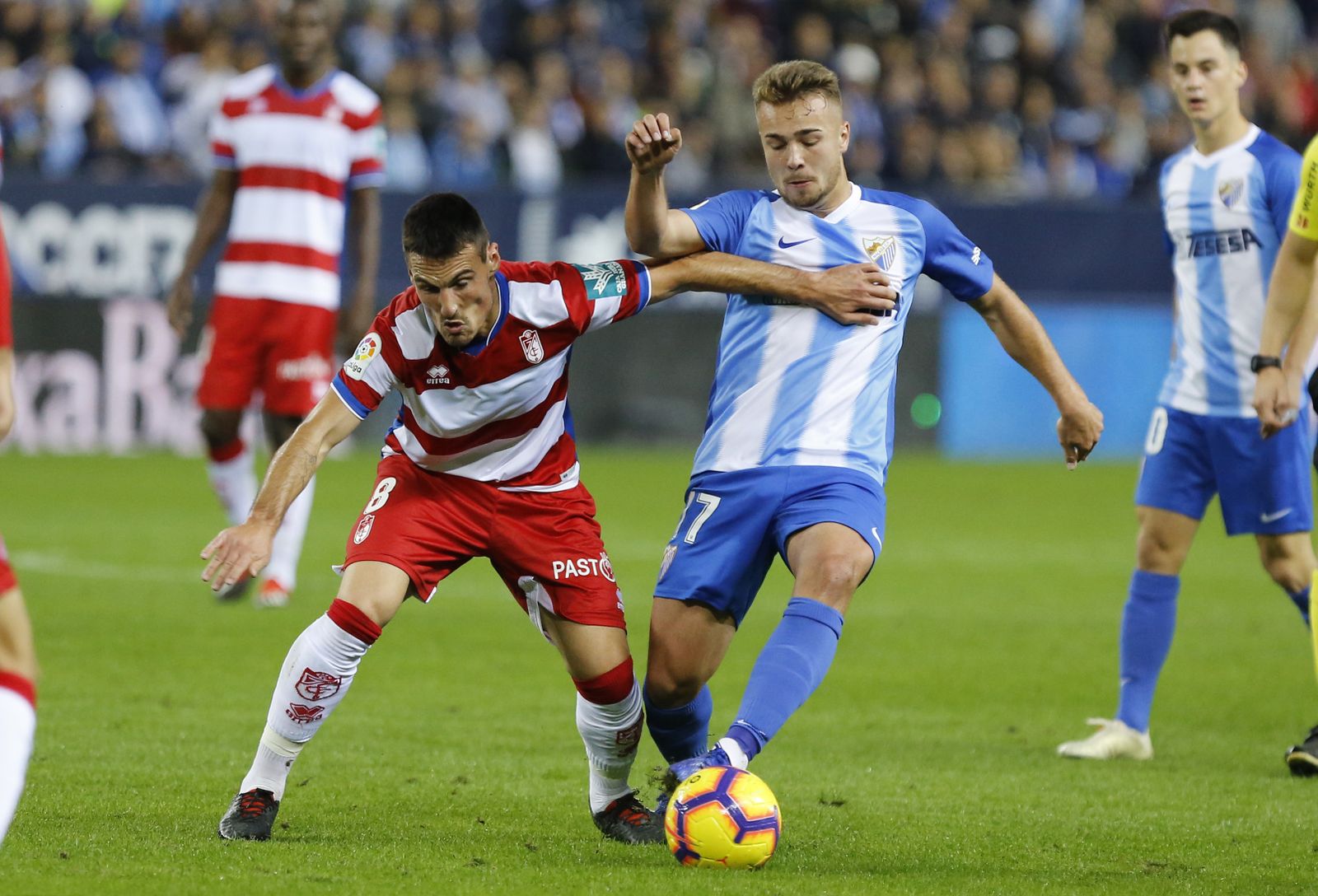 San Emeterio, centrocampista del Granada CF, aguanta la presión del jugador del Málaga Ontiveros.