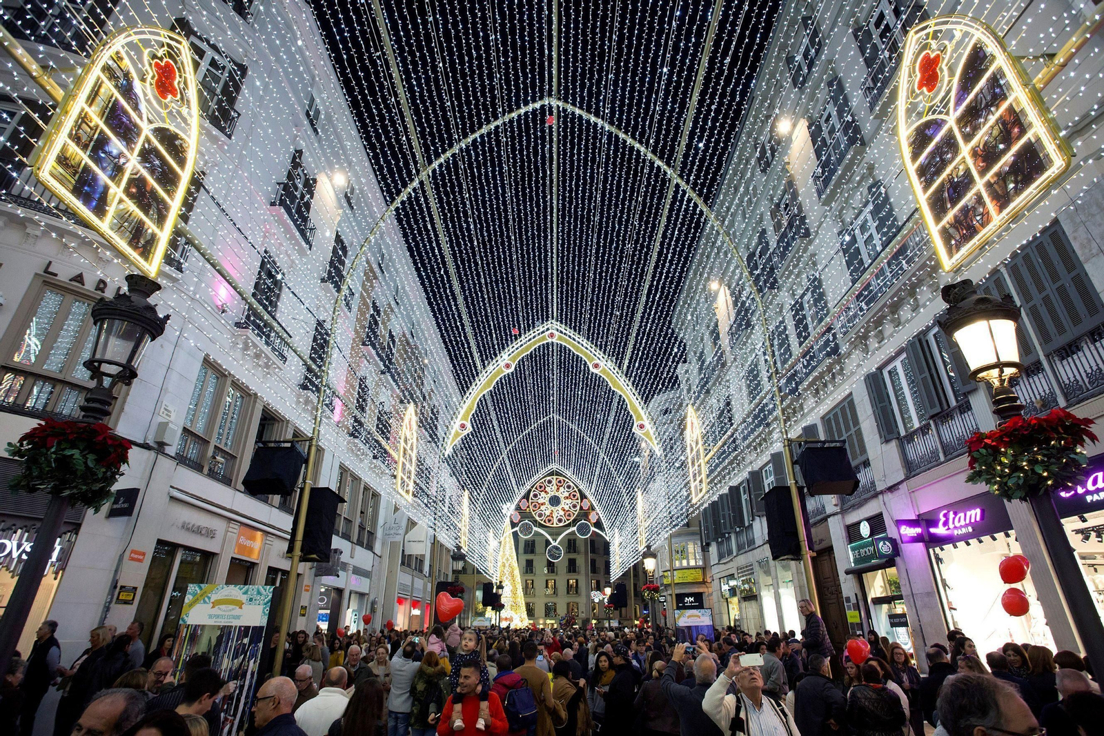 Miles de personas pasean bajo las luces de Navidad de la calle Larios.