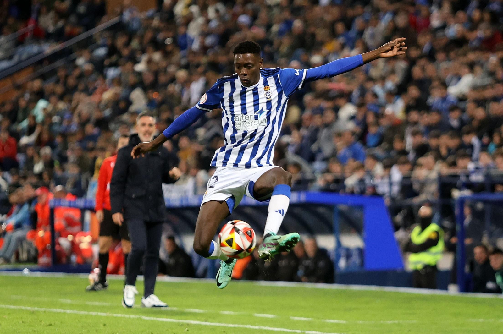 Rahim controla un balón bajo la atenta mirada de Abel Gómez al fondo.