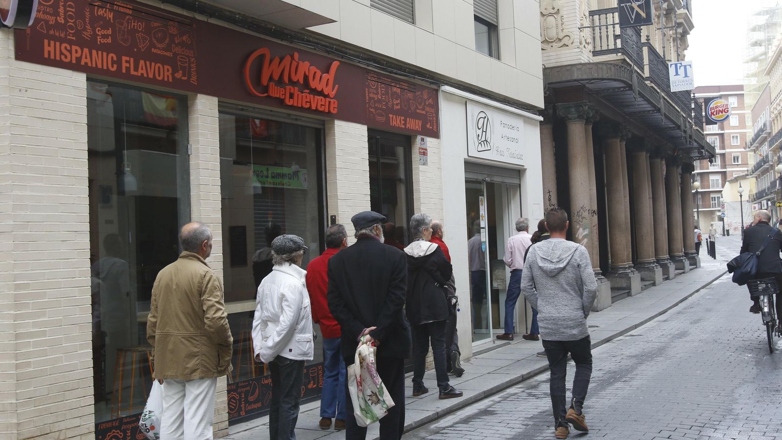 Varias personas esperan fuera de una panadería.