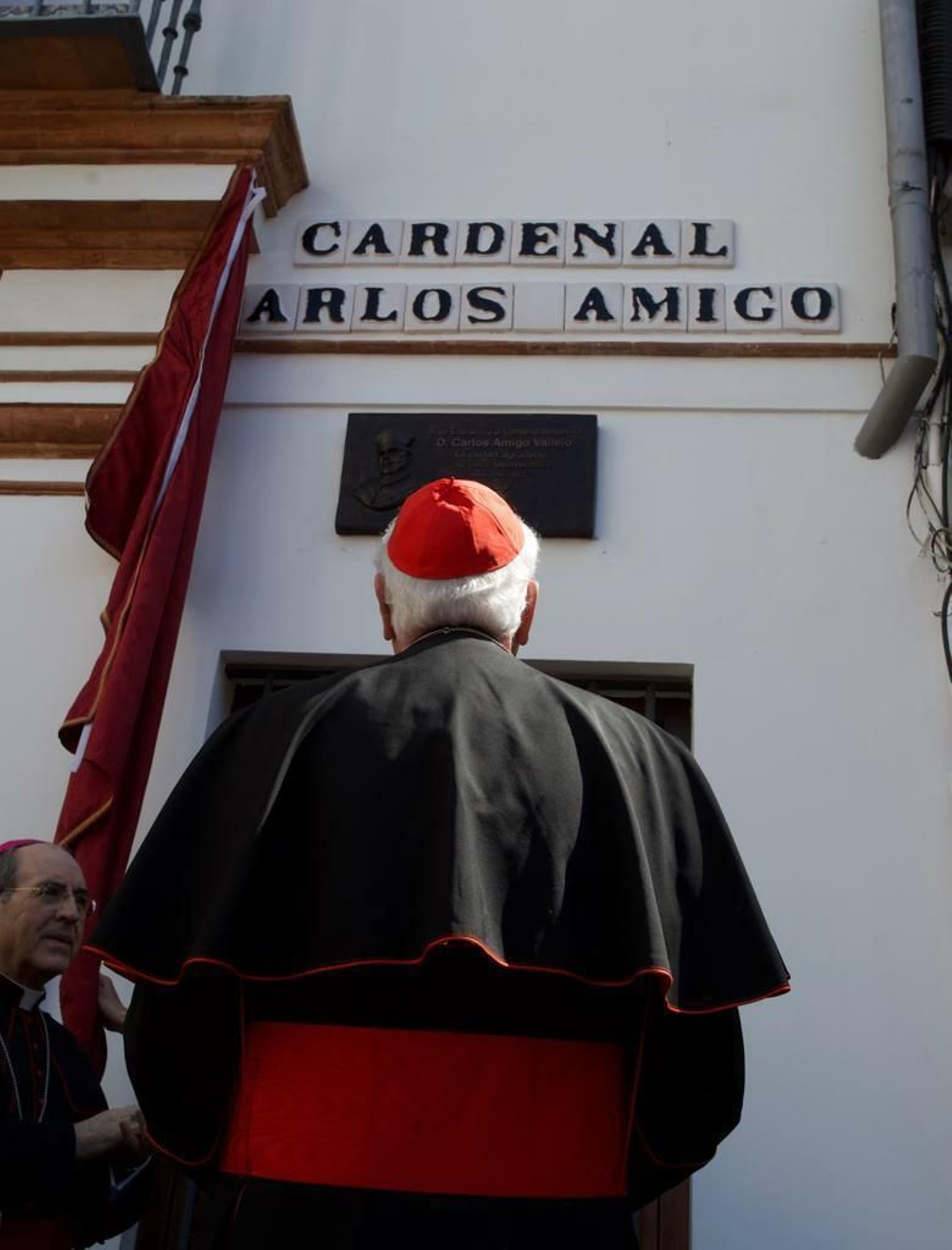 El cardenal Amigo observa el rótulo y la placa de su calle.