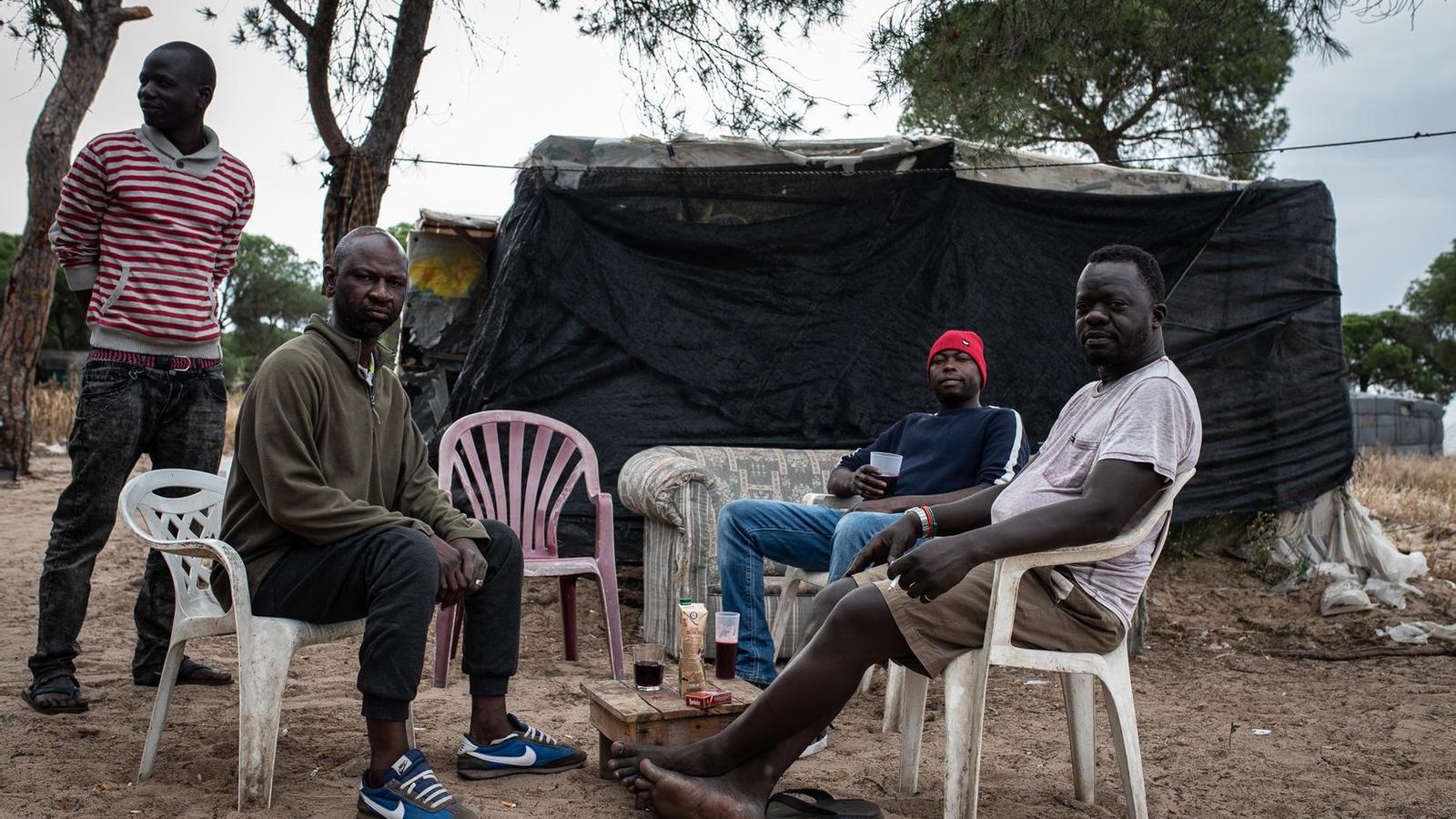 Algunos de los residentes en el asentamiento de Las Madres, en Moguer, toman un poco de vino mientras comparten una animada tertulia.
