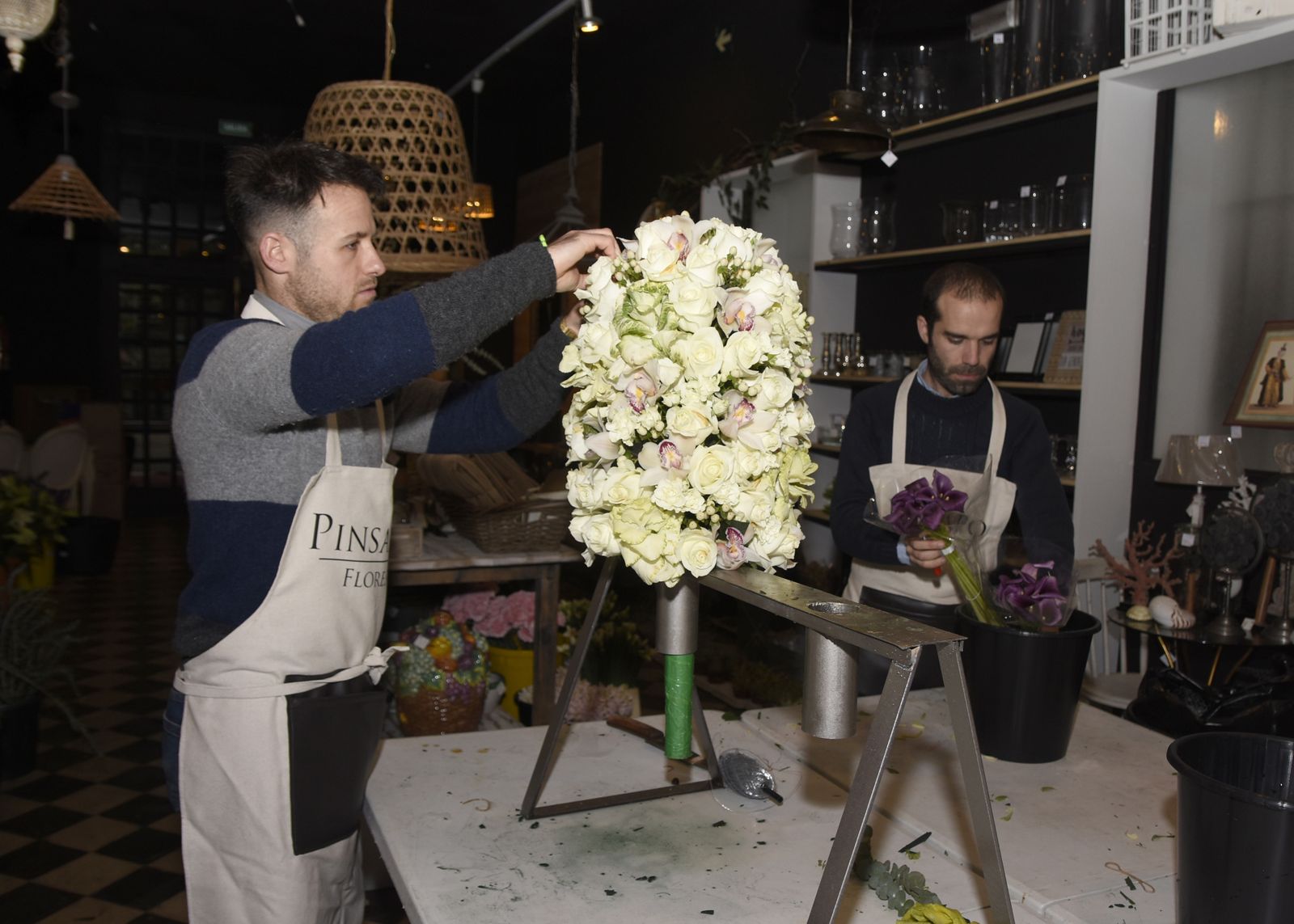 Rafael Cuevas (der.) y otro trabajador de Pinsapo preparan una piña para un palio de Virgen.