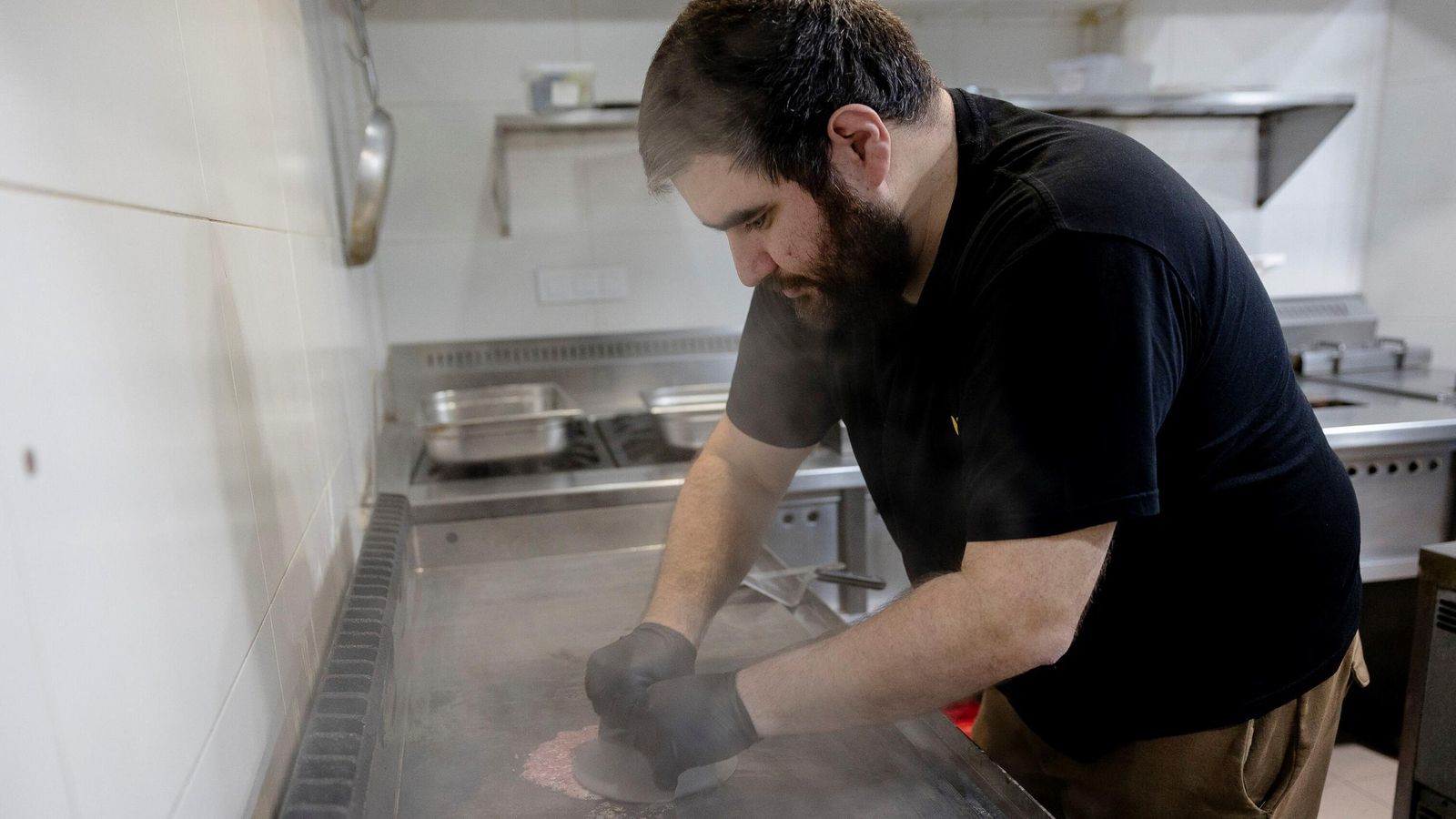 El cocinero de Seven Street Food aplasta una hamburguesa. El cocinero de Seven Street Food aplasta una hamburguesa.