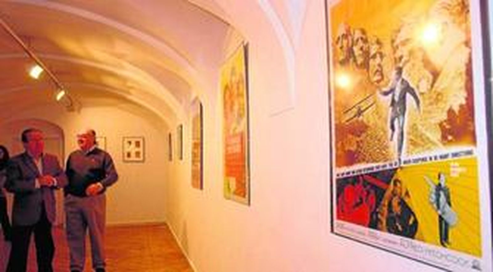 El concejal Ramón Ramírez y Esteban Gallego contemplan los carteles anunciadores de películas de Alfred Hitchcock.