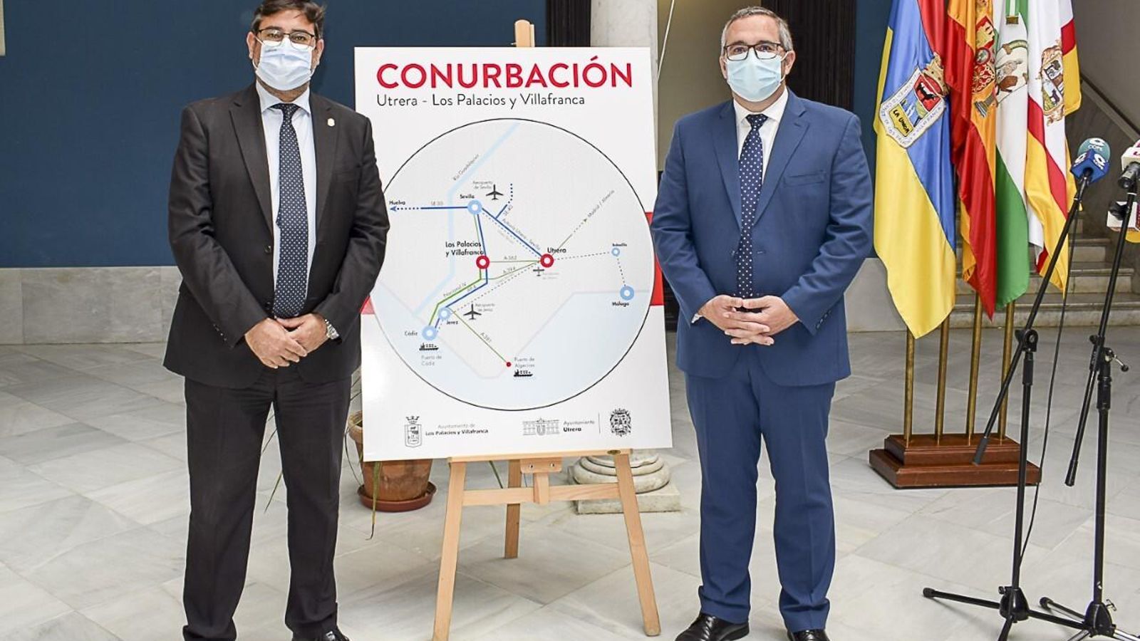 El alcalde de Utrera, José María Villalobos (PSOE),  y el de Los Palacios, Juan Manuel Valle (IU), junto a un cartel de la "conurbación".