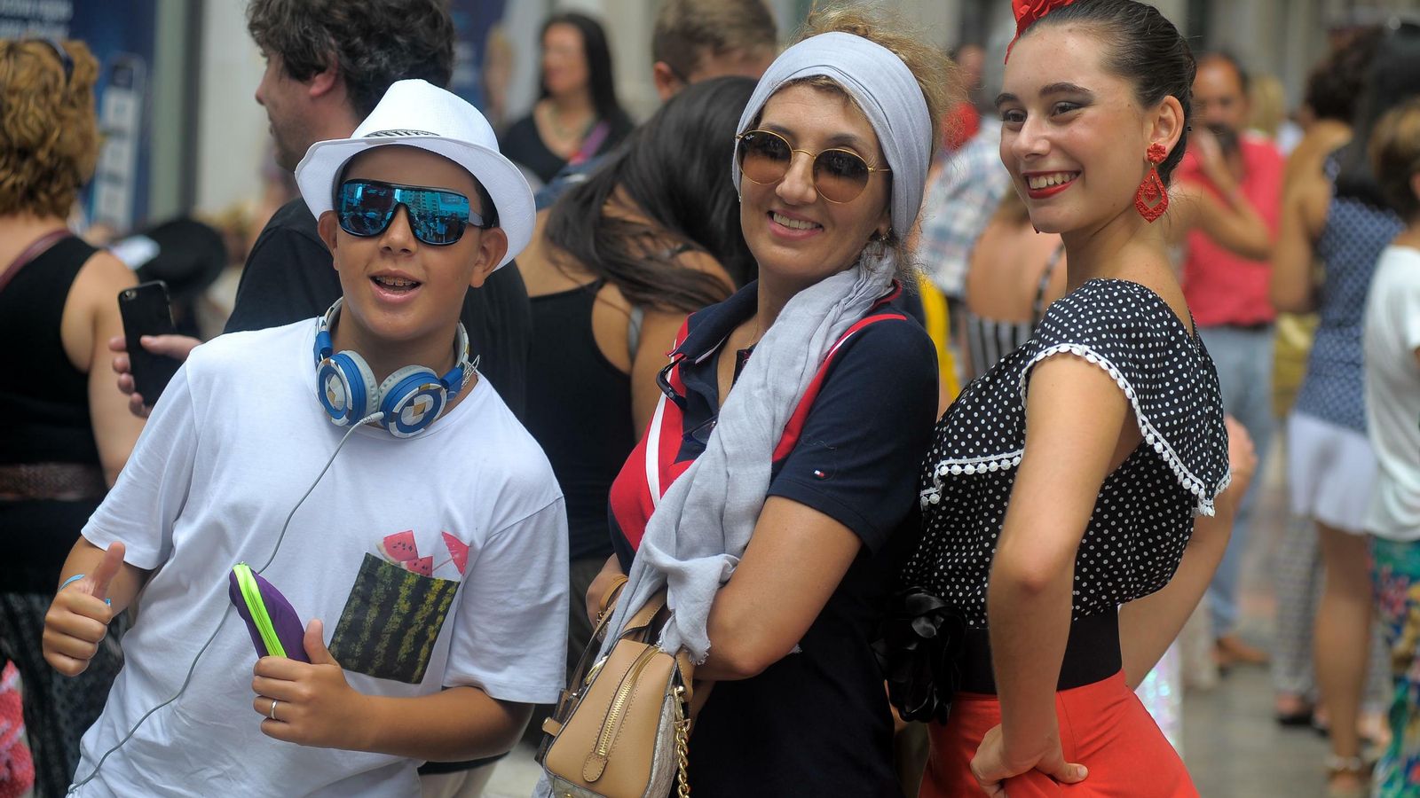 Tres turistas extranjeros posan durante la Feria de día en el centro.