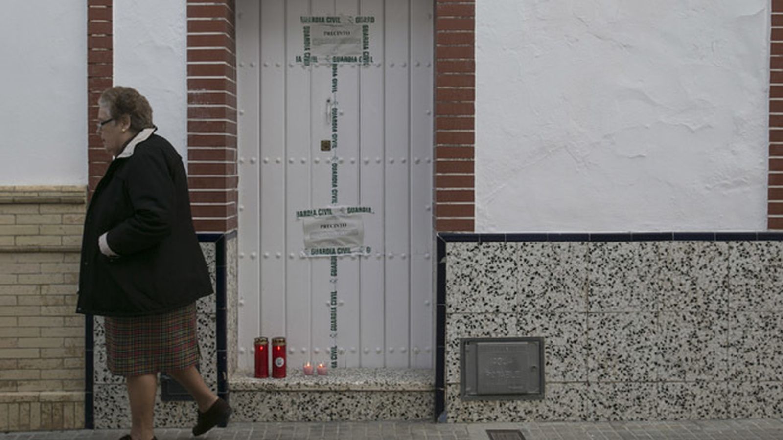 Dos velas recuerdan a las víctimas en la puerta de su vivienda.