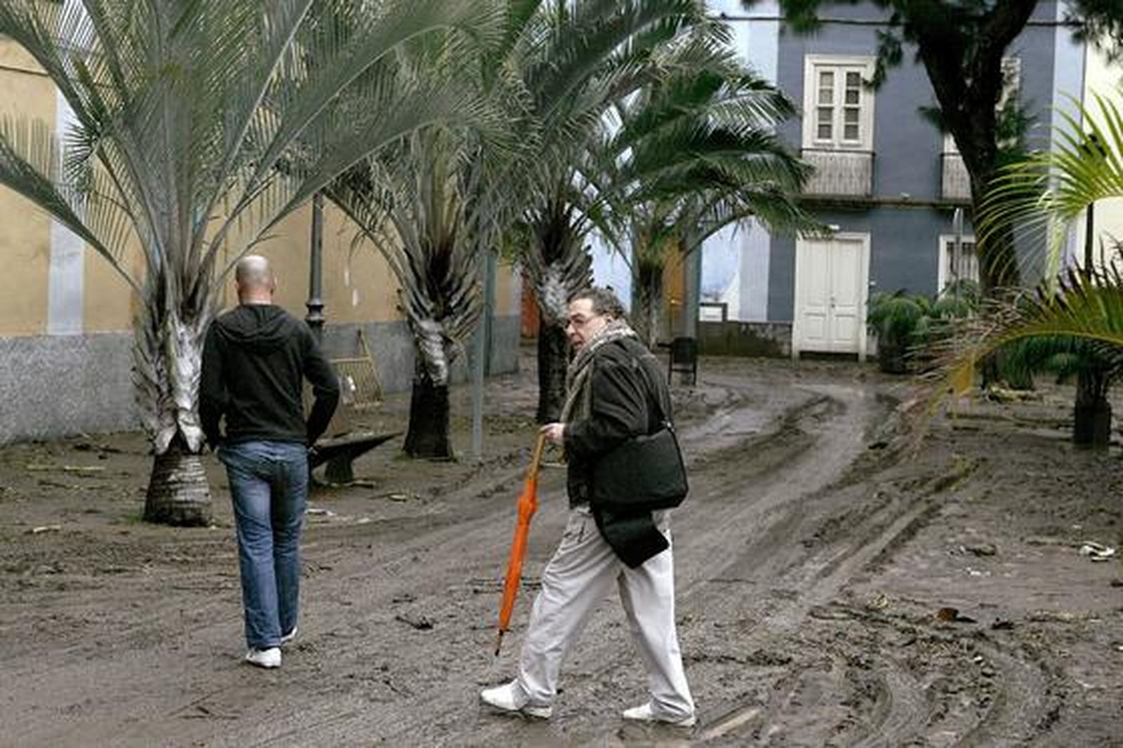 El director artístico del carnaval de Santa Cruz de Tenerife, Sergio García, camina por una calle llena de barro tras las fuertes lluvias caídas.

Foto: Cristóbal García (Efe)