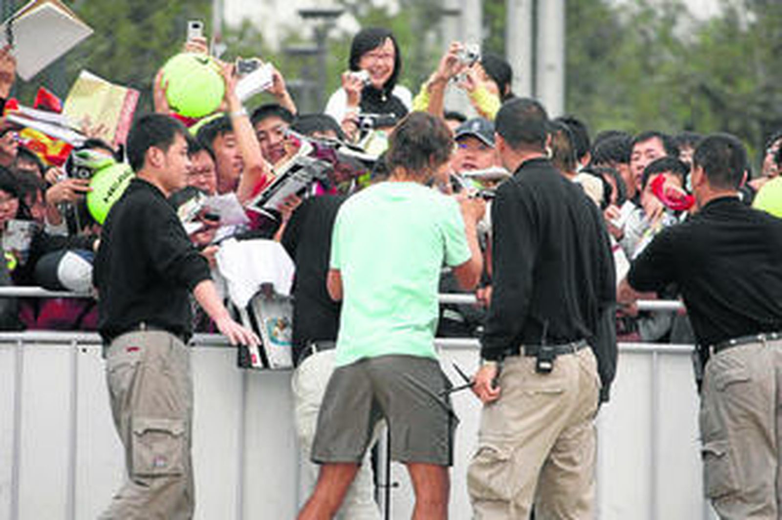 Rafa Nadal firma autógrafos tras su entrenamiento de ayer en Pekín.