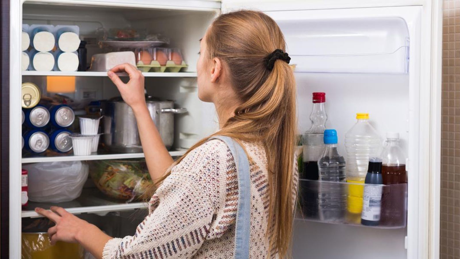 Una chica echa un vistazo a lo que contiene el interior de su frigorífico