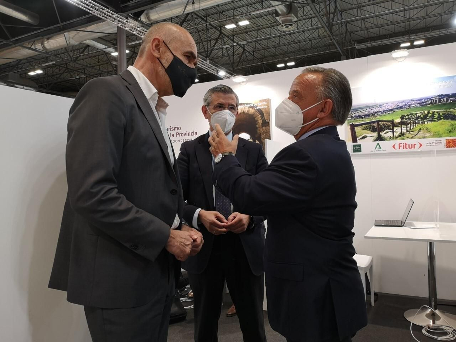 El delegado Antonio Muñoz conversa con uno de los organiadores del Arnold Sports Festival ante la presencia de José Manuel del Río, director comercial de Fibes, en Fitur.