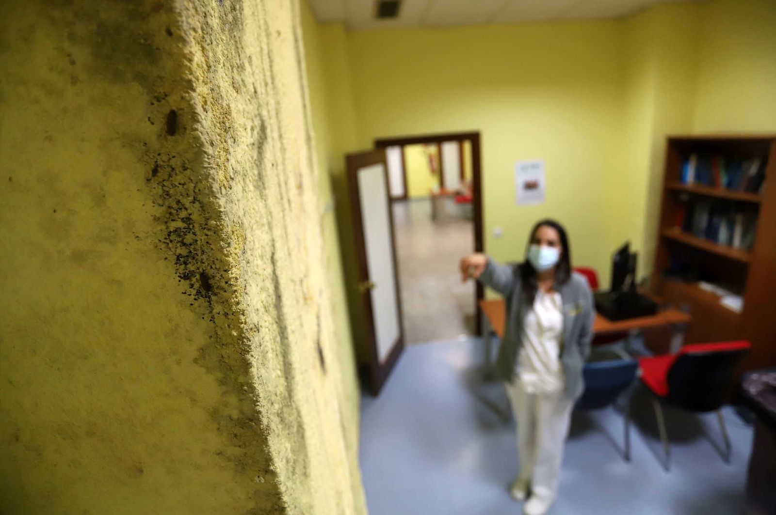 Una profesional de la Unidad de Salud Mental muestra una columna con humedades, por la que escalan dos cucarachas.