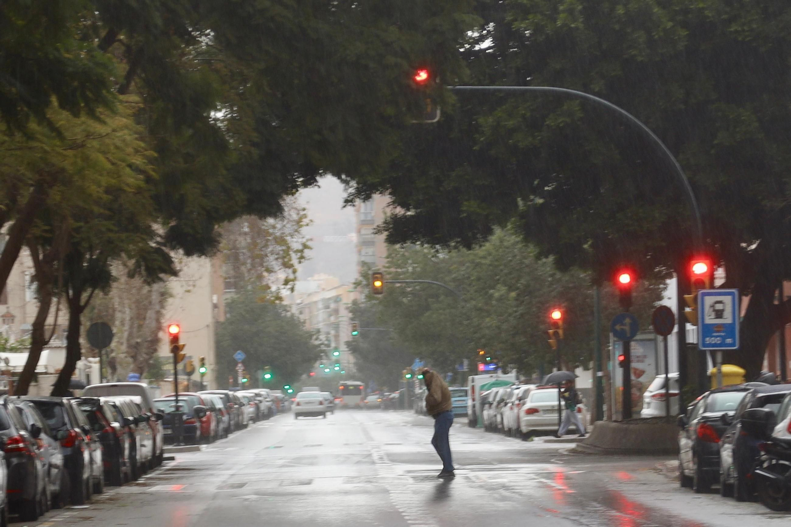 Un hombre cruza la carretera en Málaga capital durante una tormenta.