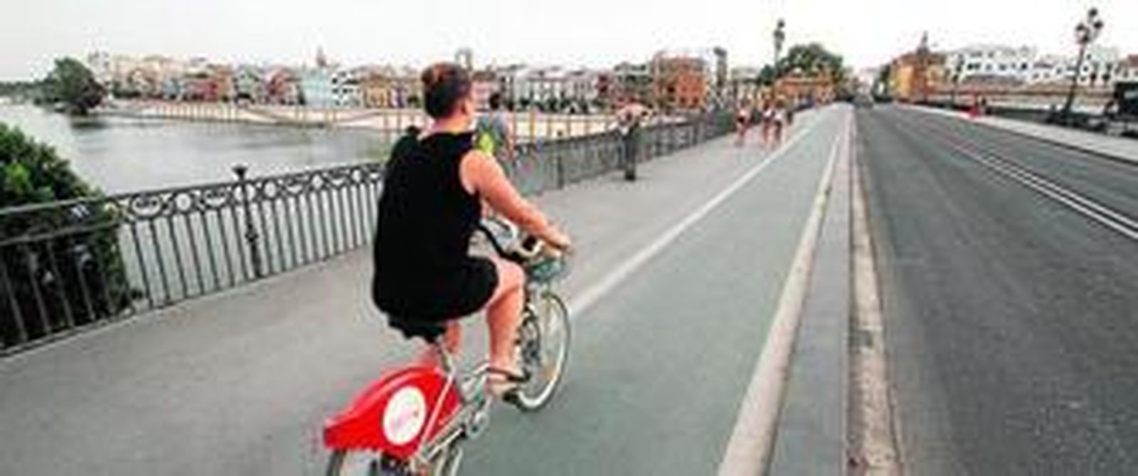 Una usuaria del servicio Sevici circula por el carril del Puente de Triana.