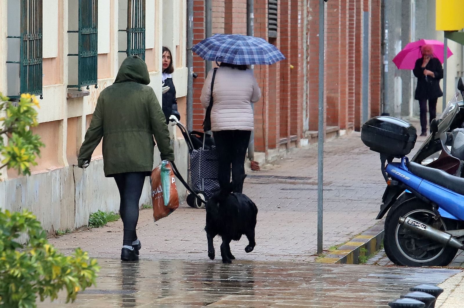 Varios onubenses pasan con paraguas por las calles de Huelva.
