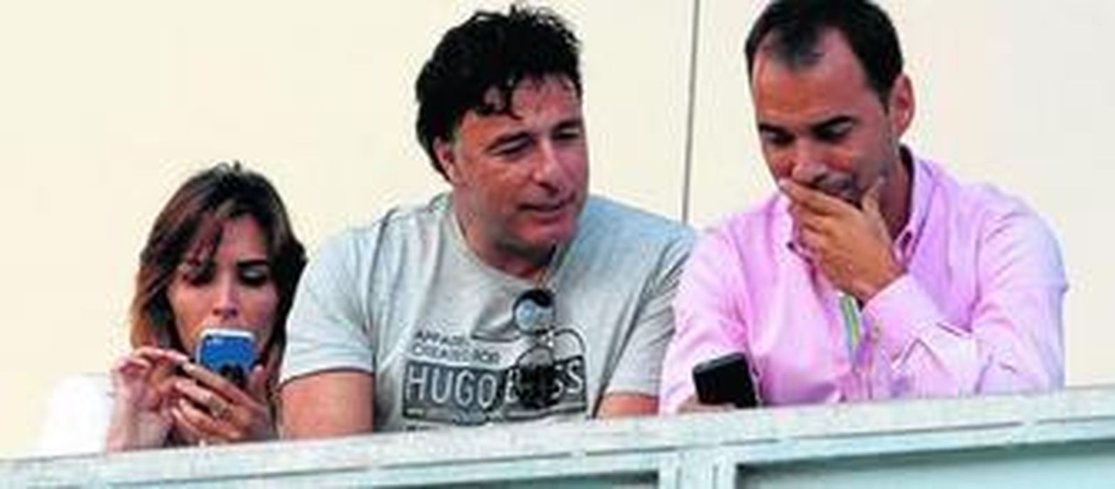 Quique Pina (c) observa el móvil de Jorge Cordero, el director deportivo cadista, estando ambos en el palco de autoridades del Ramón de Carranza.