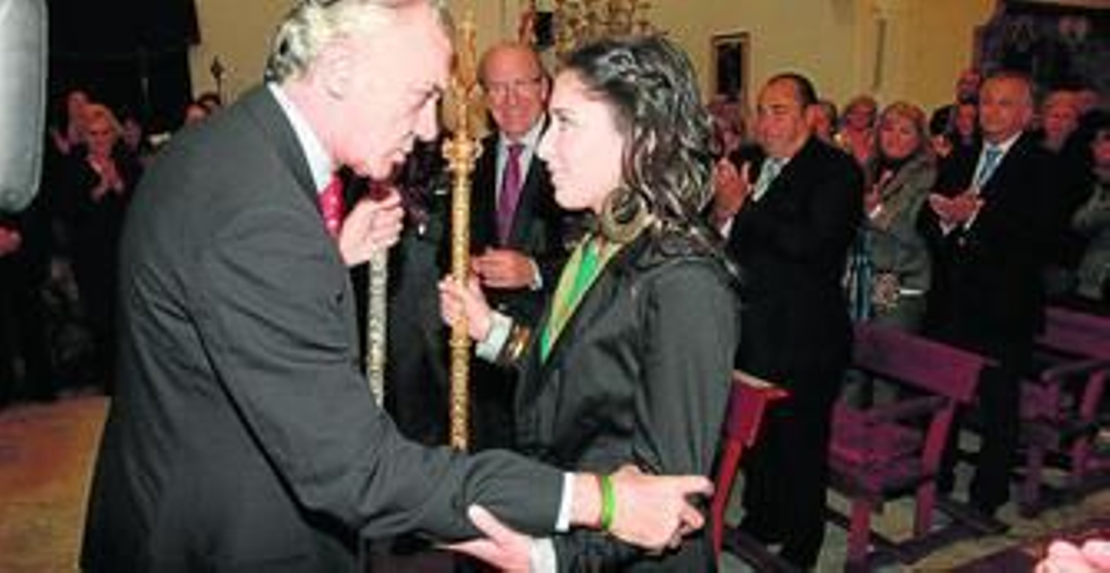 El presidente de Emigrantes arropa a la nueva hermana mayor ante la atenta mirada del alcalde y otras autoridades.