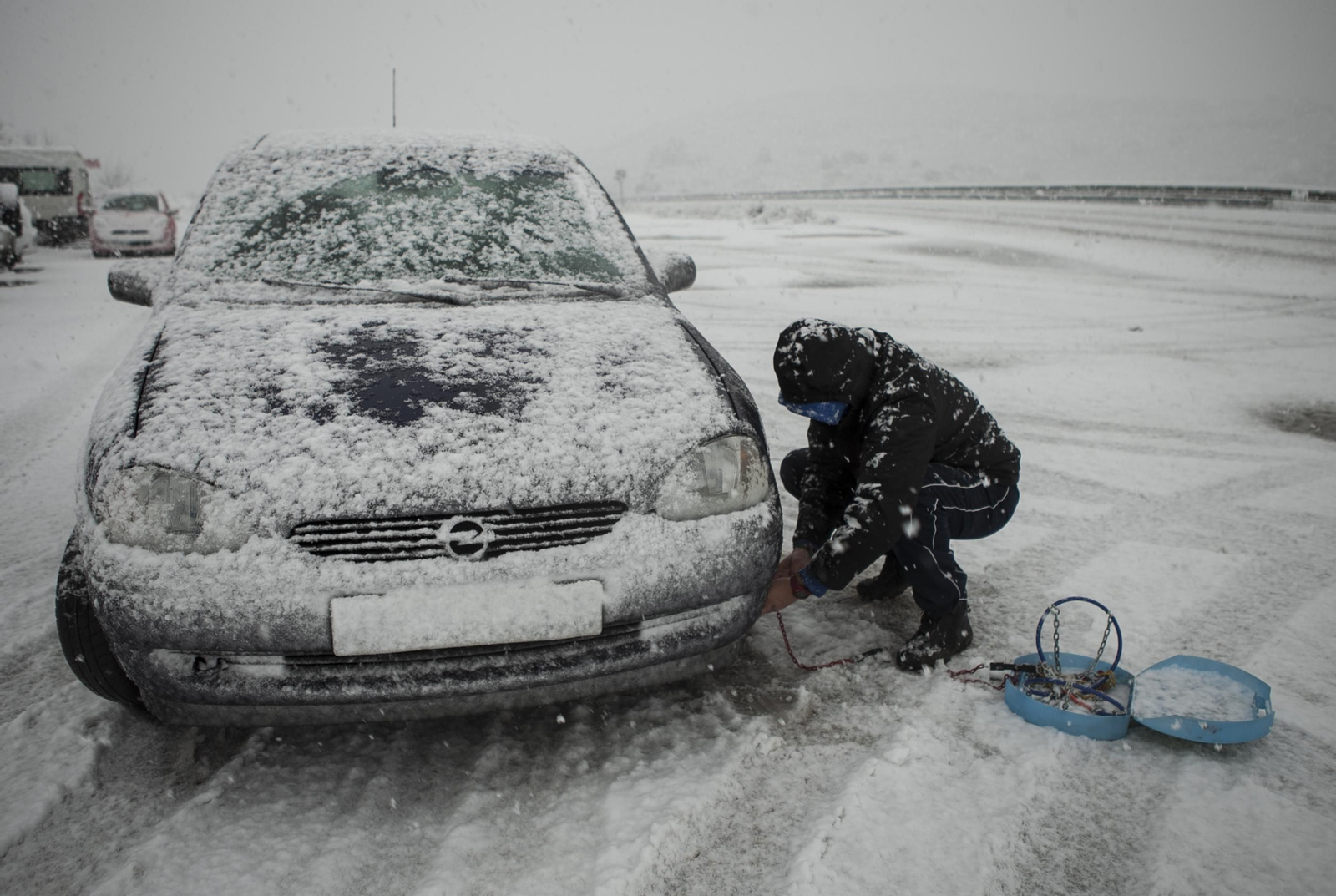 Imagen de archivo de un conductor poniendo las cadenas a su coche.