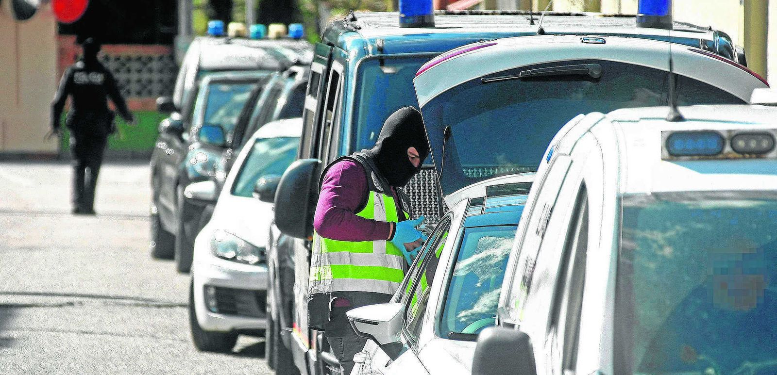 Un agente de la Policía se quita los guantes tras depositar varias cajas con documentación en el maletero de un coche, ayer en la Colonia San Miguel de Algeciras.