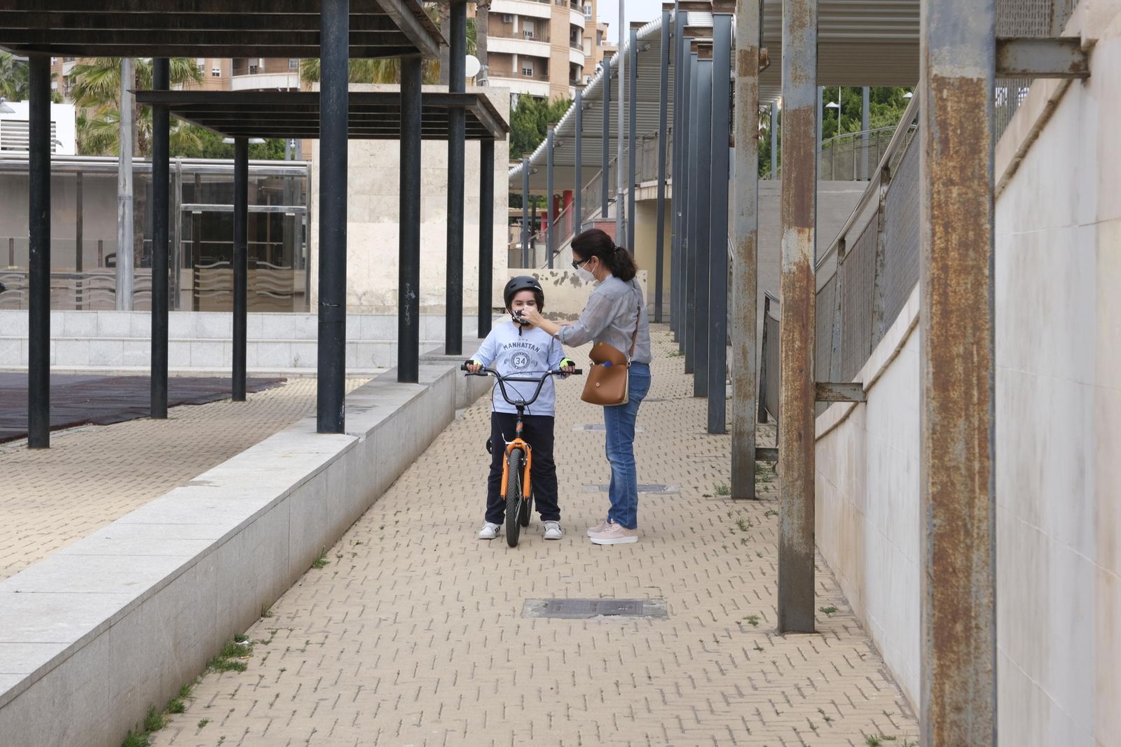 Una madre prepara a su hija para un paseo en bicicleta.