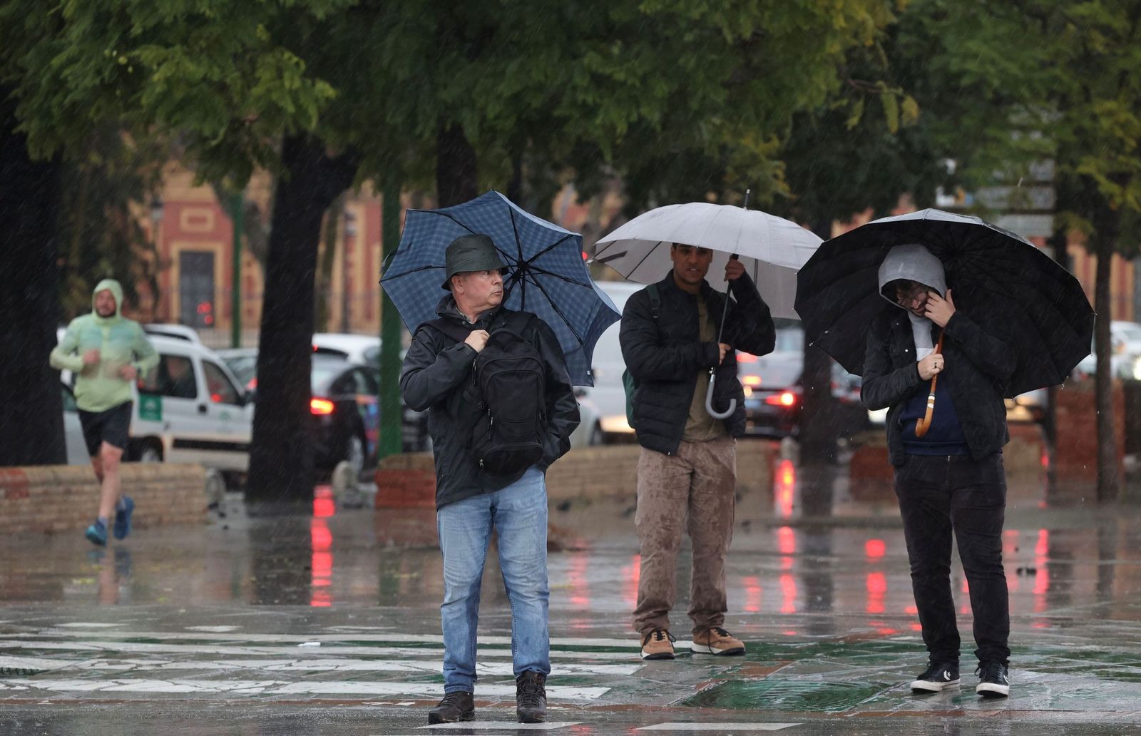 Gente con paraguas por una calle de Sevilla.