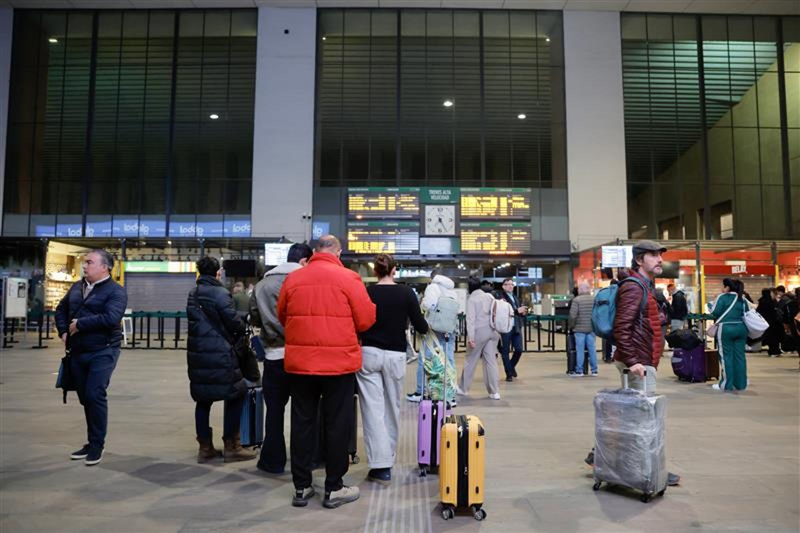 Viajeros con sus maletas esperan en Santa Justa, que recupera vida tras reanudarse la alta velocidad