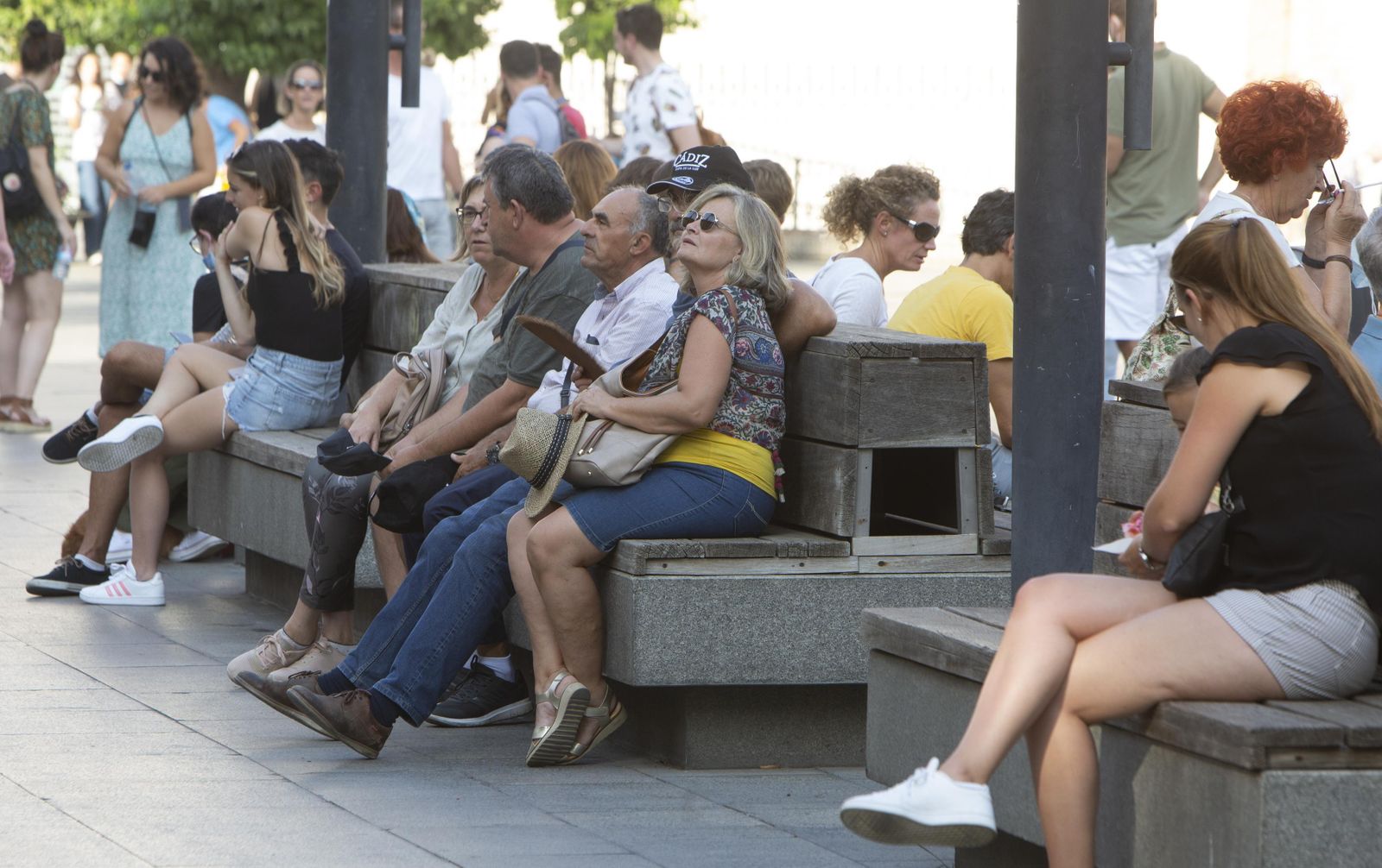Sevillanos y turistas descansan en los bancos de la Puerta de Jerez, en el centro de la ciudad.