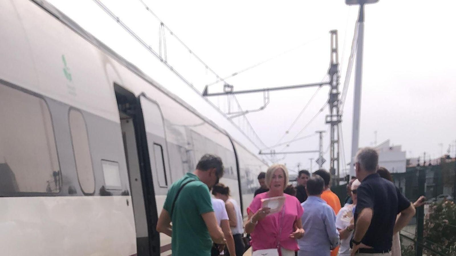 Pasajeros fuera de un tren averiado.