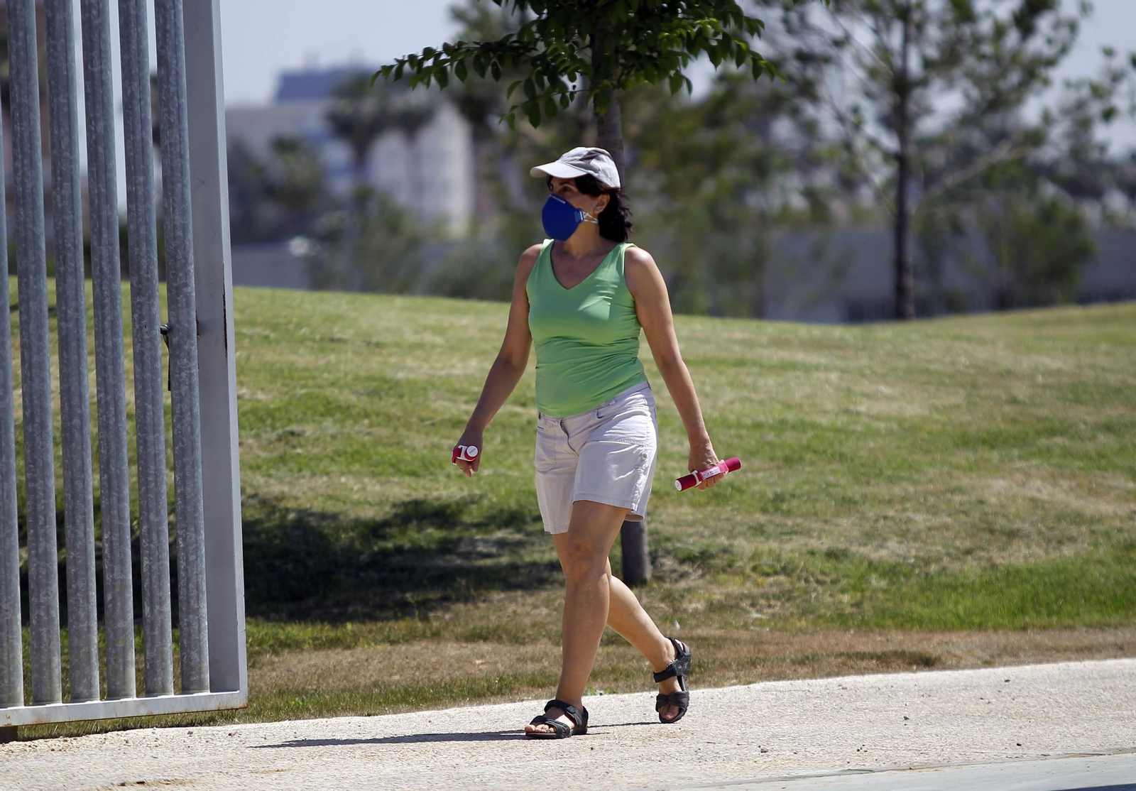 Una mujer practica deporte en un parque de la ciudad con una mascarilla.