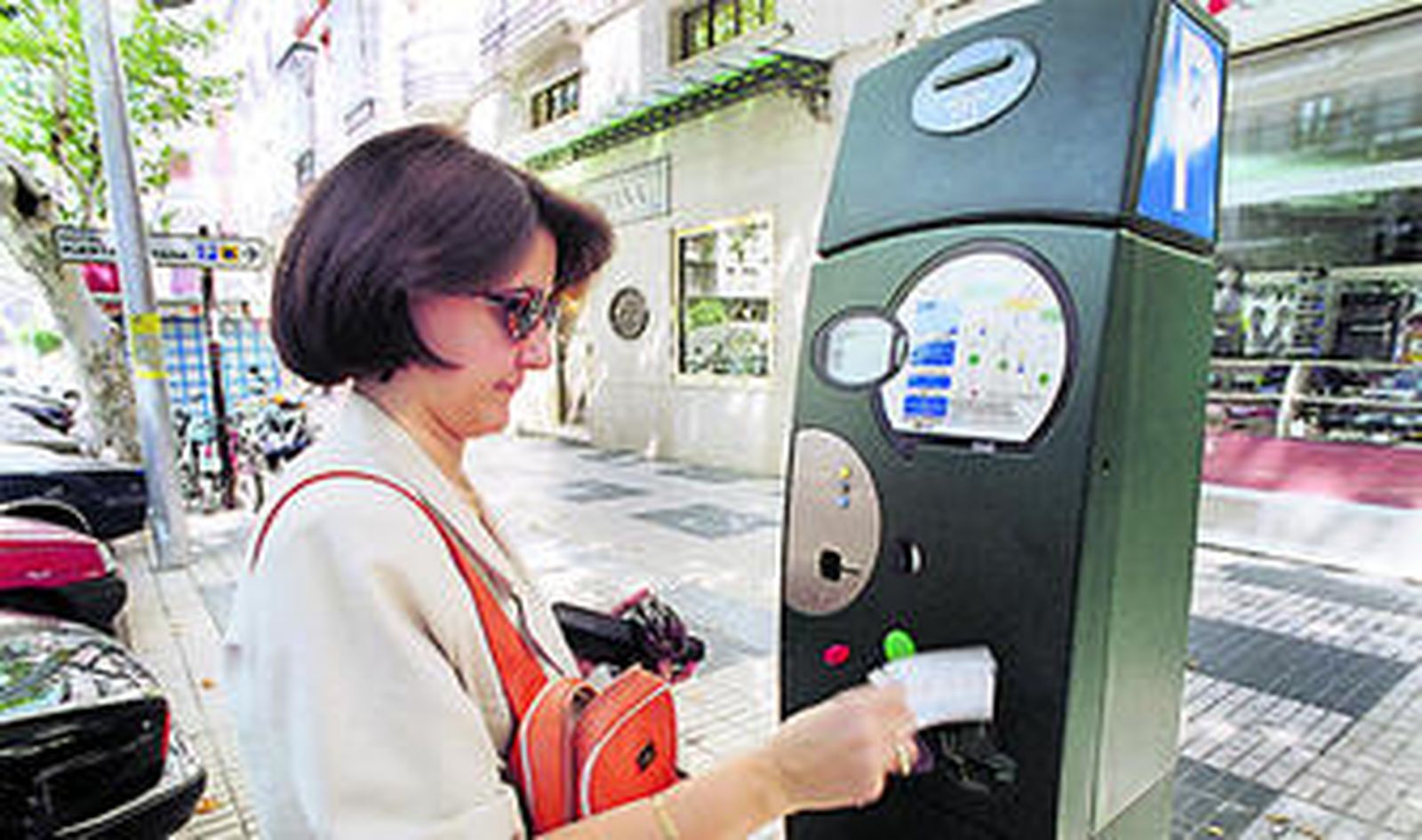 Una mujer paga la zona azul en una máquina de la calle Reyes Católicos.