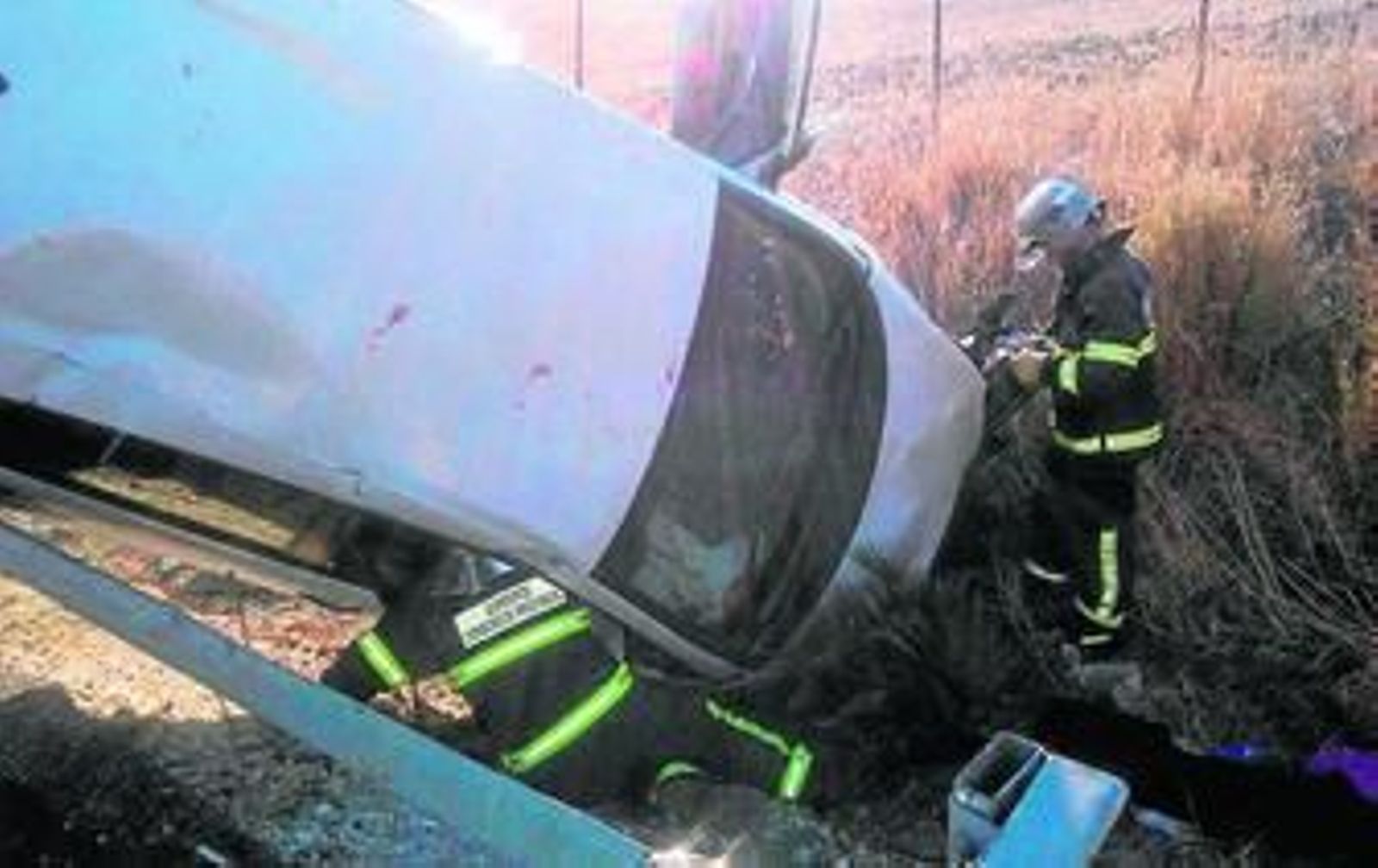 Dos bomberos junto al vehículo volcado, ayer.