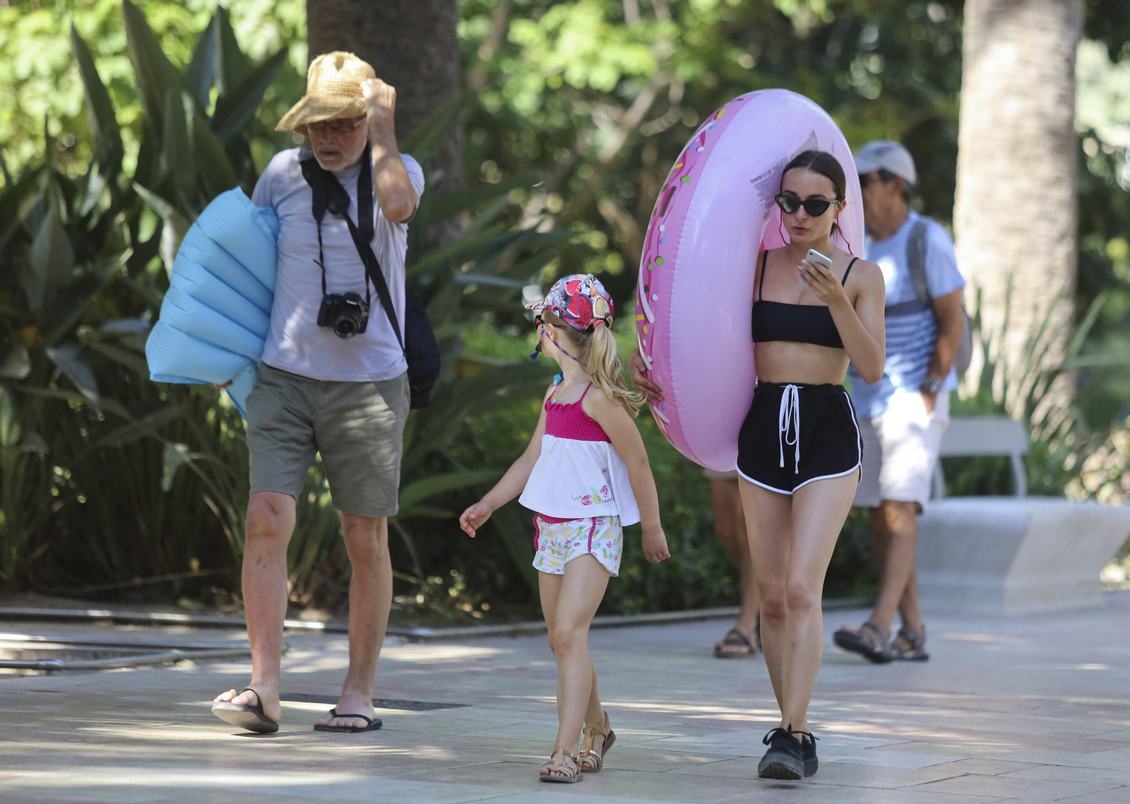 Turistas se protegen de sol camino de la playa.