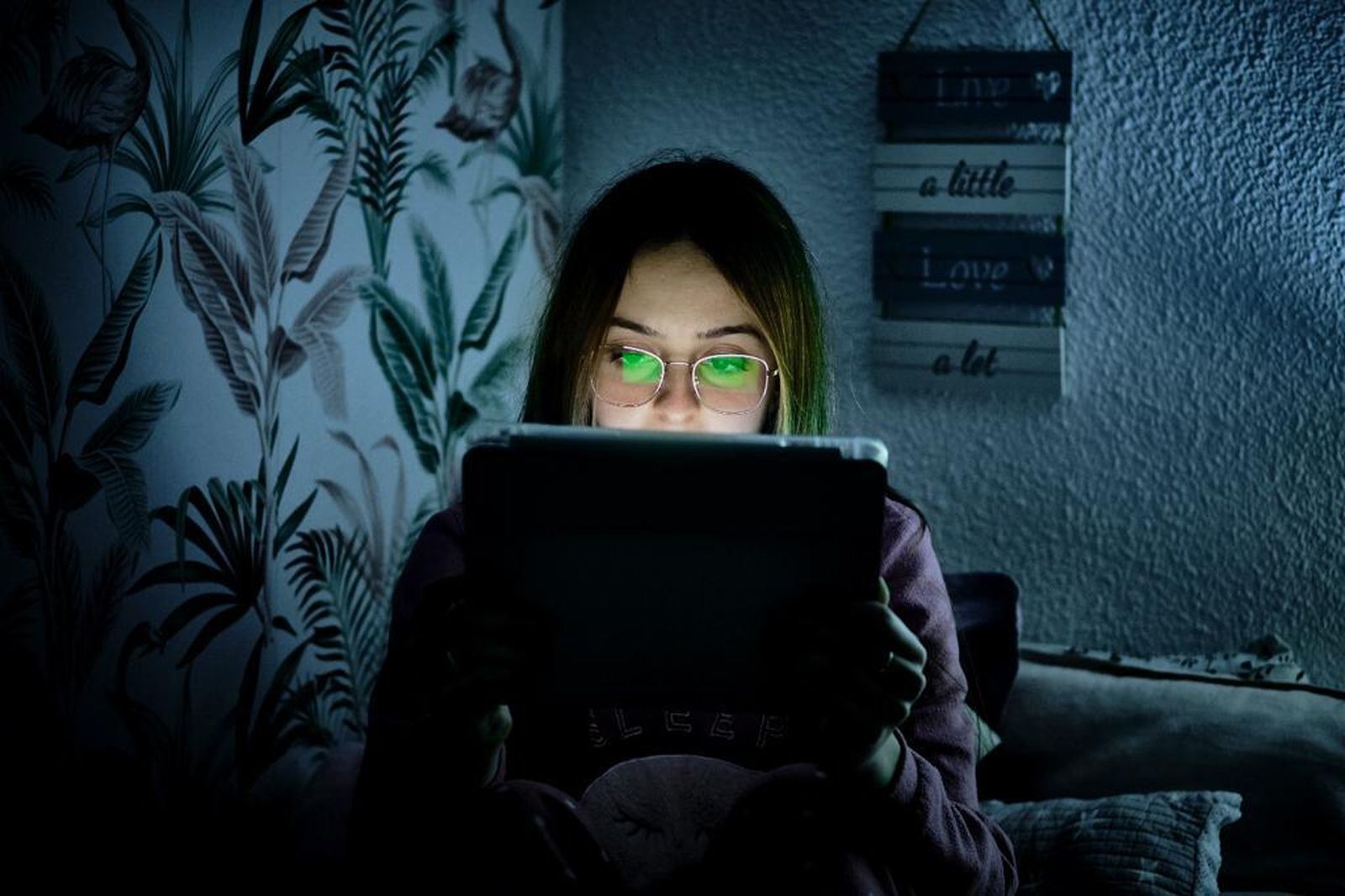 Una adolescente delante de una tableta electrónica en su habitación.