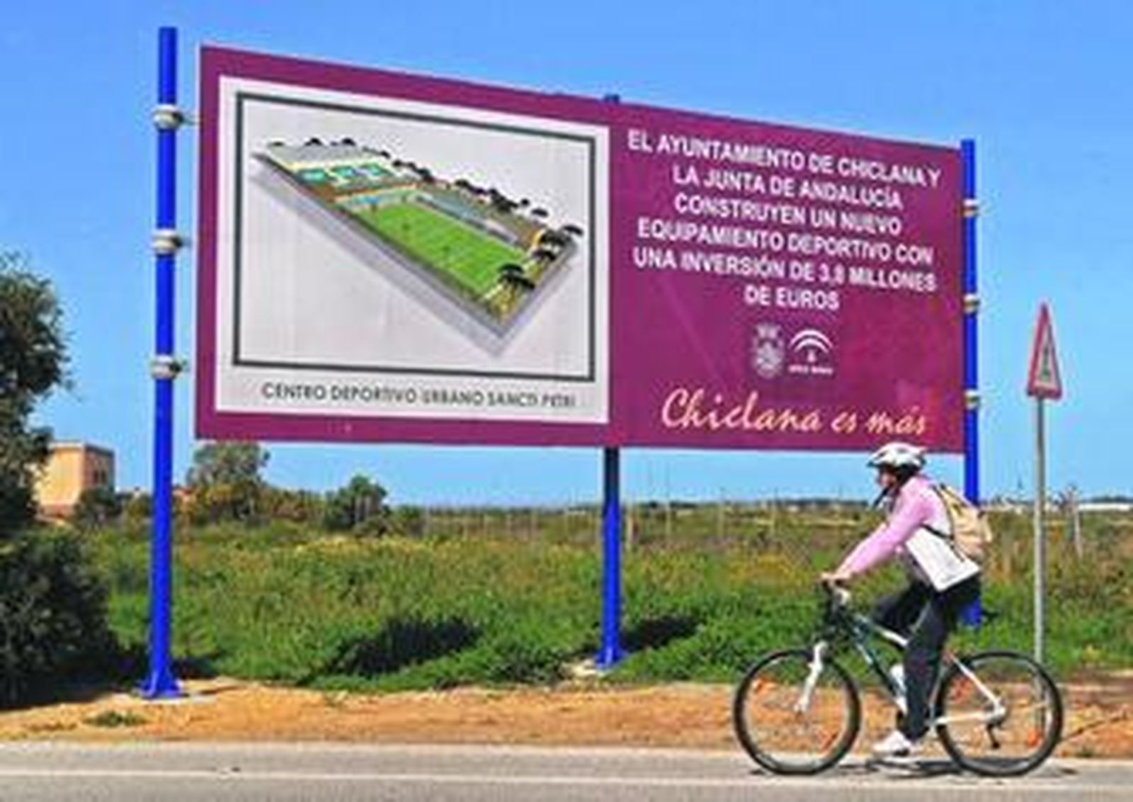 Cartel que anuncia el nuevo equipamiento deportivo en la carretera de acceso al poblado marinero.