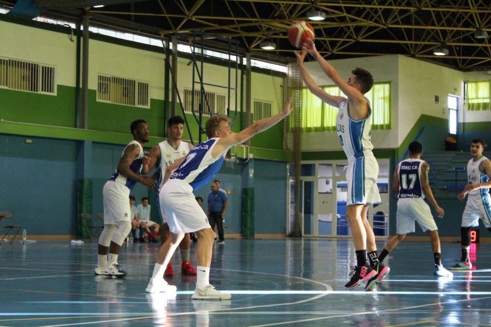 Un jugador del Mijas lanza a canasta ante la oposición de un jugador del BXCD.