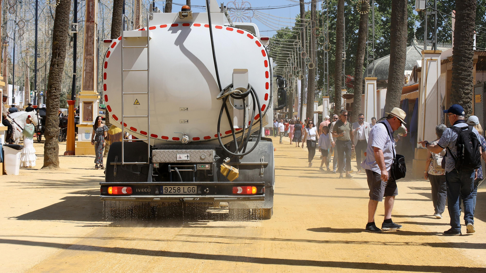 Un camión refresca el albero durante el jueves de Feria.