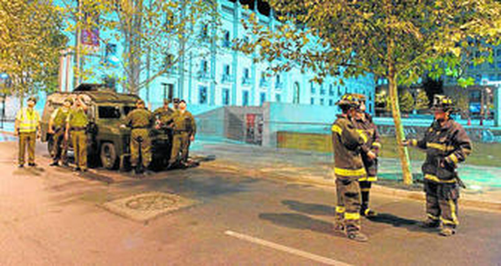 Carabineros y bomberos chilenos observan el movimiento de algunos edificios en la capital del país.