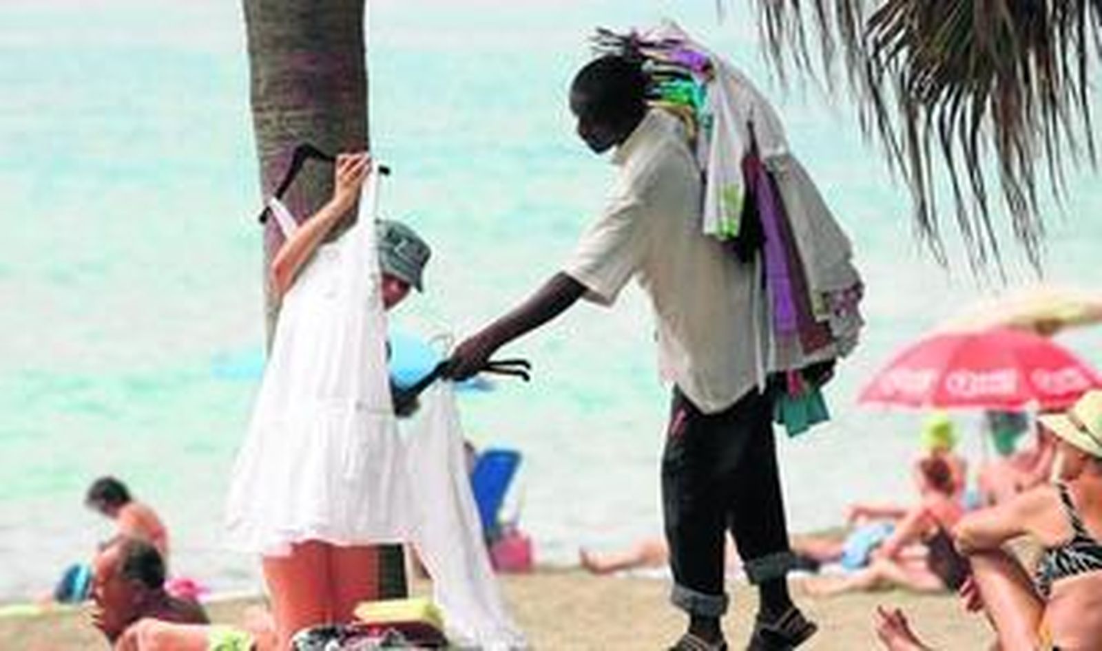 Una mujer observa en la playa algunos de los vestidos a la venta.